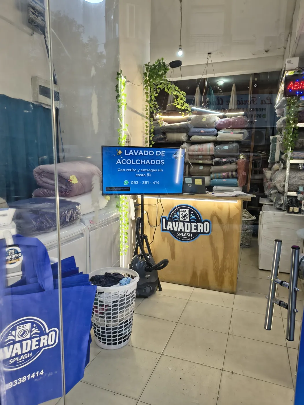 Interior del local de Lavadero Splash: el mostrador con el logo, la pantalla de lavado de acolchados y estantes con trabajos terminados